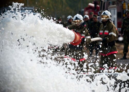 Två brandmän sprutar skum