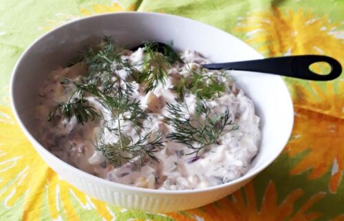 En skål med sillsallad, garnerad med dill.