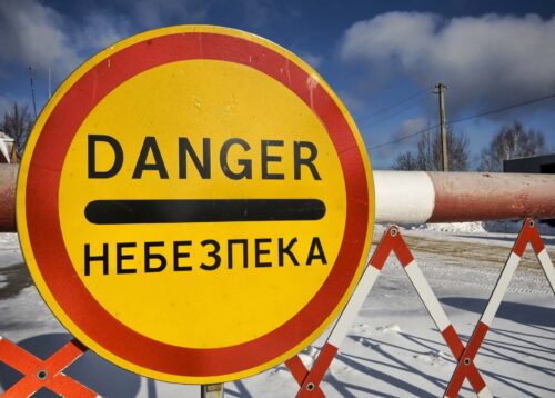 En skylt med texten "fara" på engelska och ryska.