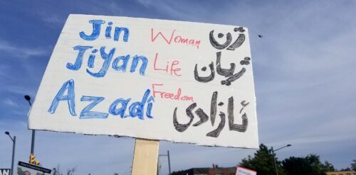 Skylt med texten "kvinna, liv, frihet" skriven på tre olika sätt