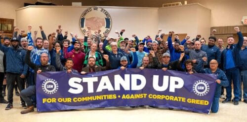 UAW-medlemmar håller upp banderoll med texten "stand up"