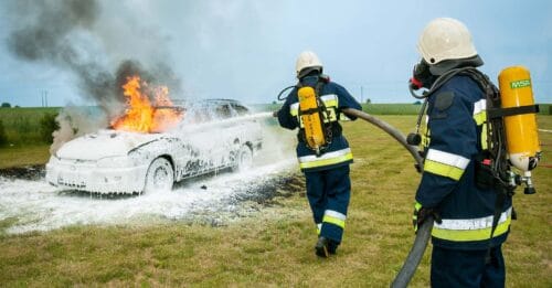 Brandmän använder brandskum för att släcka en brinnande bil