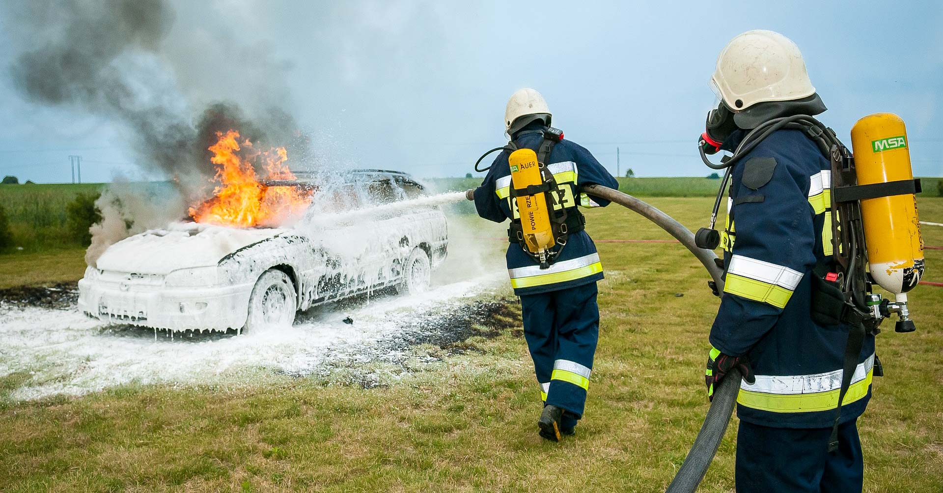 Brandmän använder brandskum för att släcka en brinnande bil