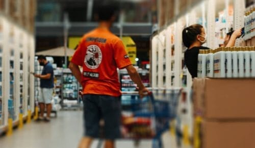 Man med kundvagn närmar sig butiksanställd